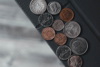 Diversas moedas antigas de diferentes países dispostas sobre uma superfície escura, representando as moedas mais valorizadas do mundo.