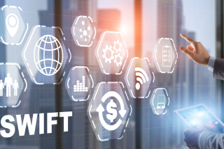 Pessoa utilizando tablet e painel digital com ícones de tecnologia e finanças, ilustrando o sistema internacional de transferências bancárias SWIFT.